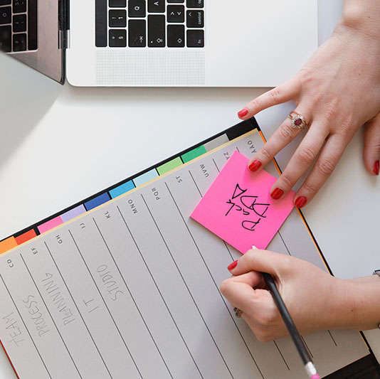 Gros plan sur les mains d'une femme écrivant Pack DDA sur un bloc-notes pour la formation Assurance : distribution et réglementation